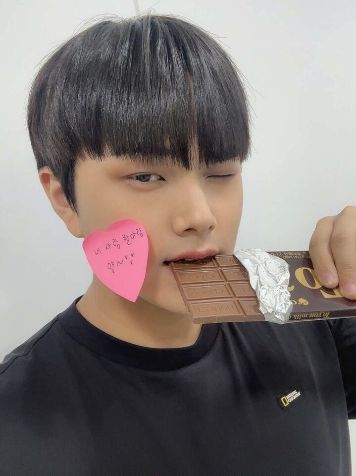 Jahan biting a chocolate bar and winking with a heart shaped sticky note on his cheek
