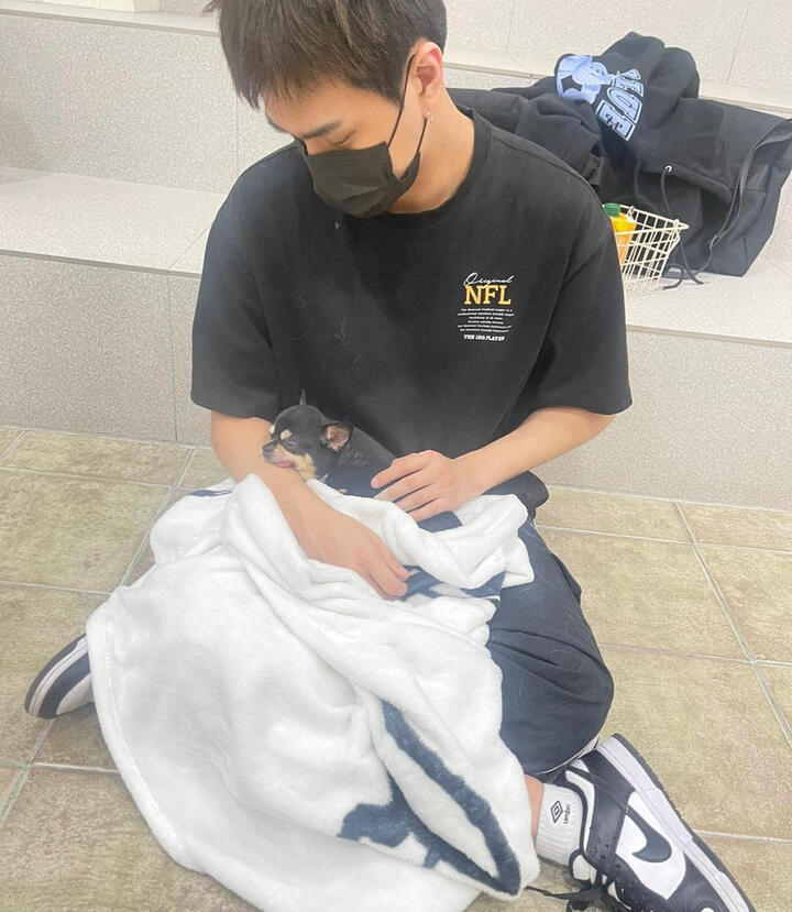 Jahan holding a very small brown puppy dog in his lap